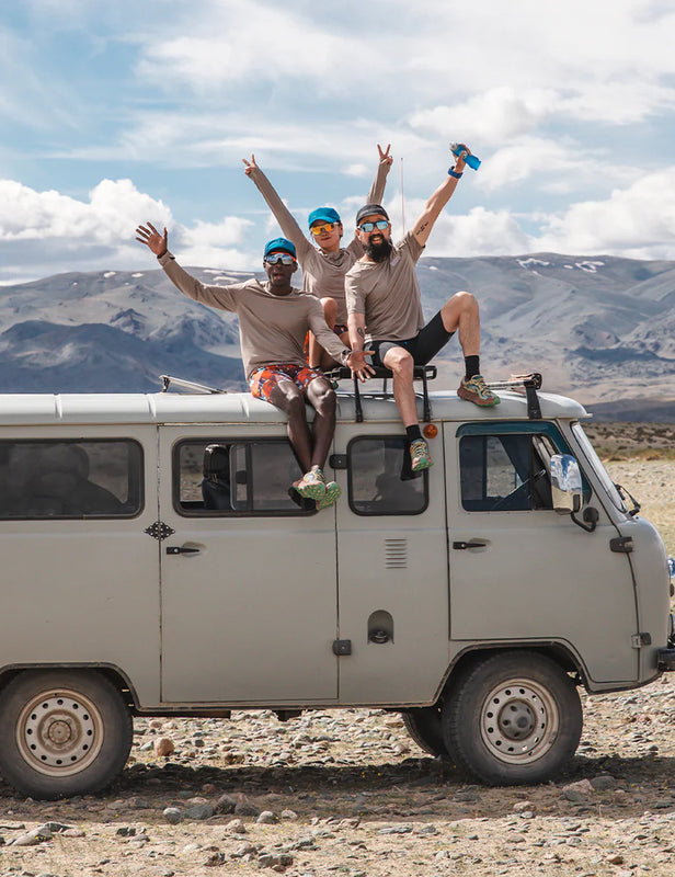 three young people sited on the roof of an old truck in a desert