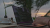 person typing on laptop, at the beach